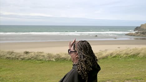 Happy-smiling-African-American-black-woman-on-ocean-beach,-waving-to-somebody-in-distance