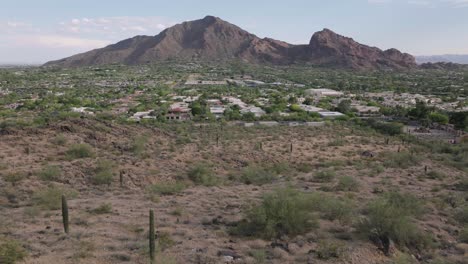 Forward-drone-view-of-desert-landscape-looking-at-Camelback-mountain-in-Paradise-valley-in-Arizona,-USA