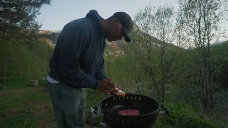 Hombre-Poniendo-Especias-Secas-En-Un-Filete-Orgánico-Fresco-Mientras-Cocina-En-La-Naturaleza