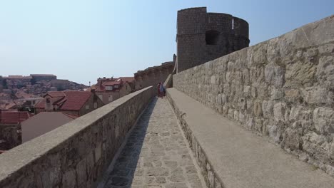 Walking-along-the-City-Walls-of-Dubrovnik,-Croatia,-on-a-sunny-day,-capturing-the-concept-of-historical-exploration-and-vibrant-travel-experiences