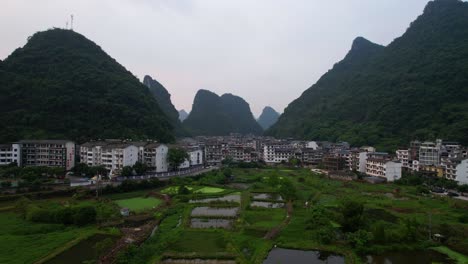 Aerial-view-of-Yangshuo-town-surrounded-by-karst-mountains-at-sunrise