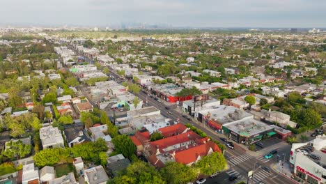 Toma-Aérea-De-Edificios-De-West-Hollywood-Bordeados-De-árboles-Y-Tiendas,-Melrose-Avenue-Y-Tráfico-Durante-El-Día.