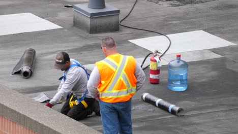 Motion-of-worker-repairing-lay-hot-tar-on-roof-surface-with-special-tools-4k-resolution