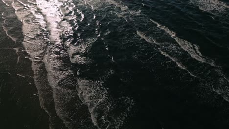 Aerial-drone-footage-of-the-sea-capturing-abstract-patterns-of-waves-illuminated-by-backlight