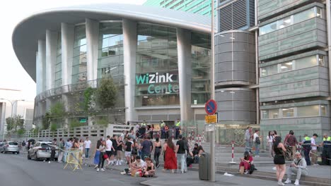 Concertgoers-stand-outside-the-WiZink-Center,-Madrid's-indoor-sports,-trade,-and-music-event-arena,-as-they-prepare-for-a-concert-in-Madrid,-Spain