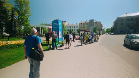 A-person-walks-through-the-city-centre-of-Daugavpils-as-a-man-drinks-alcohol-from-a-plastic-bag