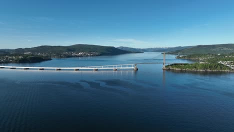 Panoramic-aerial-view-of-Nordhordland-Bridge-from-a-distance,-moving-left-with-Osterfjord-in-the-background