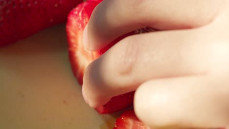 Woman's-Hand-Slicing-Through-Strawberry-in-Evening-Sunlight