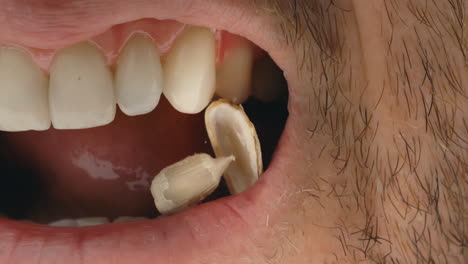 Close-up-of-man-cracking-a-sunflower-seed-between-his-teeth-in-extreme-slow-motion