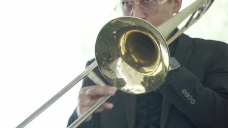 Man-with-glasses-playing-the-trombone,-trombonist-in-action