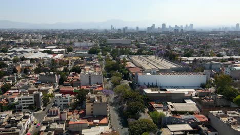 Aerial-view-establishing-on-a-sunny-day-of-a-residential-neighborhood-in-Mexico-City,-with-the-Mexican-skyline-in-the-background