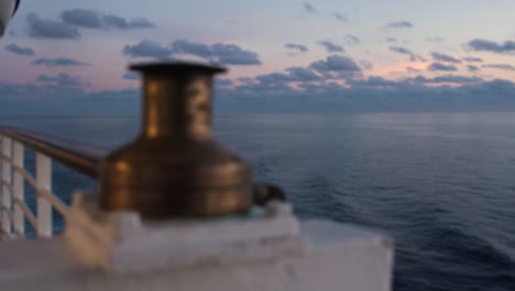 Ship-Bollard-on-Slow-Moving-Ship-through-Calm-Serene-Water-with-Beautiful-Sunset-Sky,-Cruise-Ship-Atmosphere-Life-on-Sea