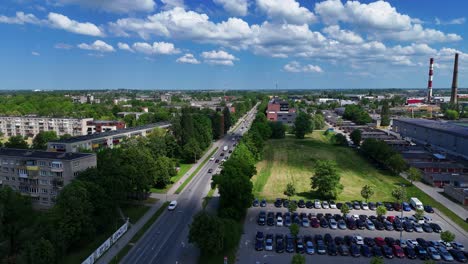 Klaipeda-cityscape-with-road,-buildings,-and-parking-lot-under-a-blue-sky,-aerial-view