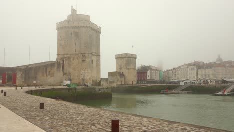 Pan-shot-of-Towers-of-La-Rochelle-in-La-Rochelle,-France-on-a-mist-day