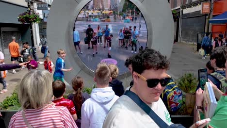 A-4K-static-shot-of-crowds-waving-to-each-other-at-the-two-way-Portal-in-Dublin-connecting-Dublin-with-New-York