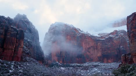 Eine-Weite-Schwenkaufnahme-Der-Berggipfel-In-Zion-Mit-Schnee-Und-Wolken,-Die-Sie-Bedecken