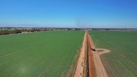 A-tractor-dragging-a-small-road-grader-and-scooping-soil-from-a-dirt-road