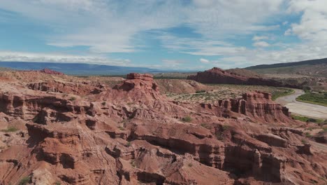 Cars-driving-past-the-impressive-red-rock-formations-of-Quebrada-de-las-Conchas,-Cafayate,-Salta