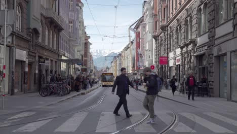 Public-transport,-busses-and-trams,-and-pedestrians-on-Anichstrasse-street-in-the-city-center-of-Innsbruck,-Tyrol,-Innsbruck