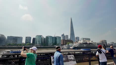 Tourists-walk-along-the-Thames-with-a-view-of-The-Shard-and-modern-buildings