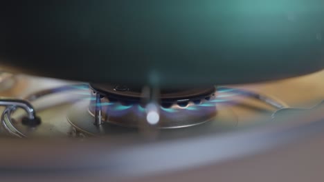 Close-up-of-gas-stove-burner-turning-on-with-pot-on-top