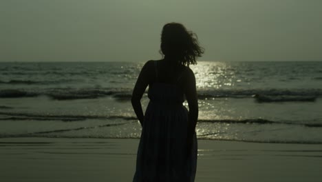 woman-standing-by-the-sea-with-her-hair-blowing-in-the-breeze