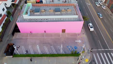 Drone-Shot-Above-Pink-Wall-in-Fashion-Shopping-District-of-Melrose-Avenue-Los-Angeles,-People-Posing-at-Popular-Photo-Destination-in-Daytime