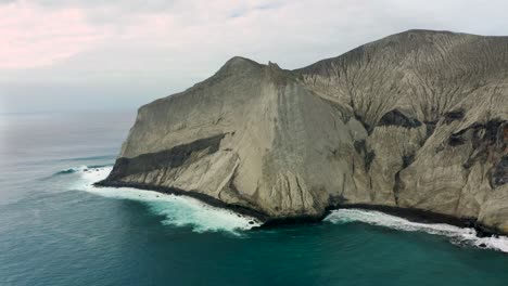 Steep-rocky-cliffs-drop-off-into-coastal-waters-on-overcast-day,-San-Benedicto-Revillagigedo-Islands-Mexico