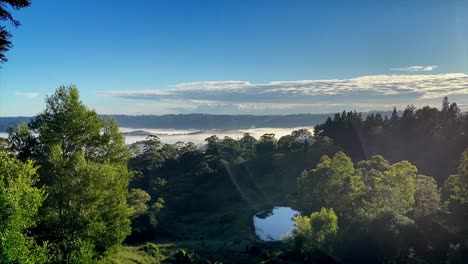 Breath-taking-dawn-sunrise-in-the-Sunshine-Coast-Hinterland-at-Maleny,-Queensland-with-fog-ebbing-away-through-the-valley-as-the-sun-comes-up-illuminating-the-drifting-fog