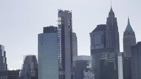 pan-from-the-iconic-skyscrapers-of-Manhattan-to-the-tranquil-harbor,-capturing-the-Statue-of-Liberty-in-the-distance,-contrast-between-the-city's-towering-architecture-and-its-serene-waterfront