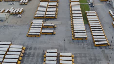 Vista-Por-Drones-De-Una-Fila-De-Autobuses-Escolares-Amarillos-En-Un-Gran-Estacionamiento