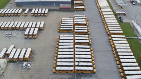 Vista-Por-Drones-De-Una-Fila-De-Autobuses-Escolares-Amarillos-En-Un-Gran-Estacionamiento