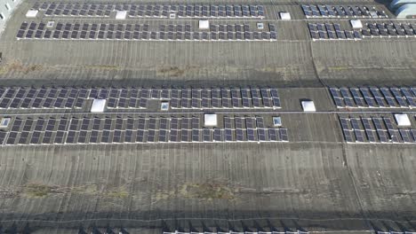 Toma-De-Drones-De-Los-Paneles-Solares-En-El-Techo-De-Un-Edificio-De-Producción-En-Un-Día-Soleado,-Alejar