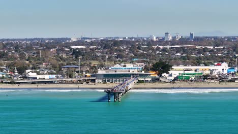 Aerial-view-beachfront-and-people-enjoying-sunny-day,-seaside-with-buildings