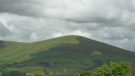 Wolkenschatten-Ziehen-über-Abgerundete-Englische-Landschaft-Grün-Fiel,-Während-Schwere-Niedrige-Dicke-Wolke-Vorbeizieht