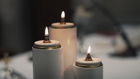 Close-up-of-three-lit-candles-on-a-table,-providing-a-warm-and-serene-ambiance