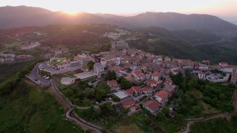 órbita-Aérea,-Sol-Brillando-En-Un-Pequeño-Pueblo-En-La-Cima-De-Una-Colina,-Castel-San-Pietro