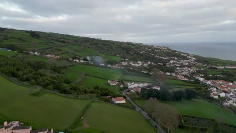 Aerial-view-of-a-village-a-lush-countryside-in-front-of-the-ocean