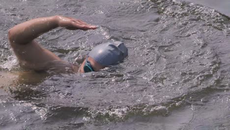 Indian-man-swimmer-swimming-in-river-open-water-with-swimming-cap-and-goggles-close-up-slow-motion