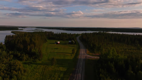 Aerial-tilt-shot-tracking-a-car-driving-on-the-road-E75,-summer-sunset-in-Lapland