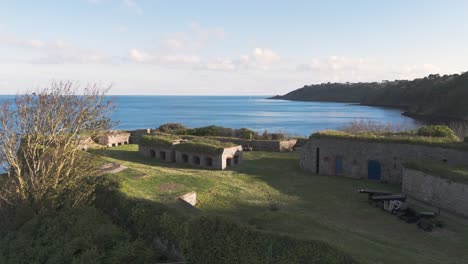 Detailed-forward-drone-footage-over-Clarence-Battery-Guernsey-flying-over-historic-armoury-towards-Fermain-Bay-on-calm-bright-sunny-day