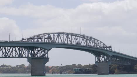 Aerial-Shot-of-Auckland-Harbour-Bridge-with-traffic-on-it,-vehicles-are-moving,-New-Zealand,-Cloudy-weather