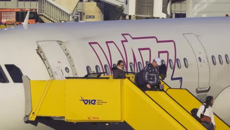 People-disembarking-from-Wizzair-Airbus-aircraft-at-Vienna-International-Airport-using-boarding-stairs,-front-door