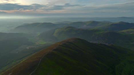 Ancient-rounded-glaciated-forested-mountains-and-fells-misting-into-lowlands-at-golden-hour