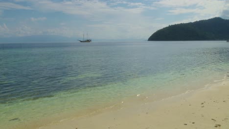 Klassisches-Segelboot-Schwimmt-In-Der-Ferne-Auf-Dem-Türkisfarbenen-Wasser-Von-Raja-Ampat,-Indonesien