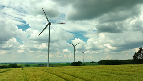 Aerial-footage-showing-three-wind-turbines-standing-tall-over-expansive-fields-under-a-partly-cloudy-sky