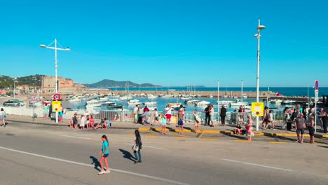 People-enjoying-sunny-day-at-Le-Mourillon,-marina-in-background,-Toulon,-France