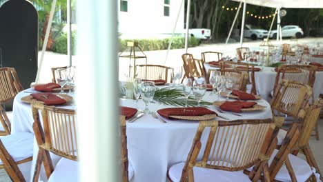 Slow-pan-of-tables-and-chairs-wedding-venue-decor-and-flowers-outdoor-seating-sandy-beach-engagement-seating-with-tables