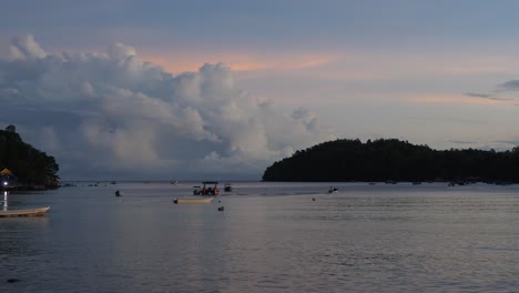 Picturesque-sunrise-scenery,-boats,-ocean-water,-silhouette-peninsulas