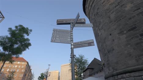 People-walking-under-a-cluster-of-signs-in-Nuremberg,-Germany